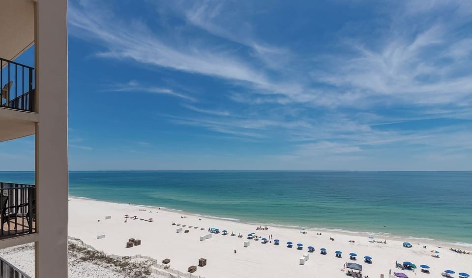 Gaze at the inviting shoreline with colorful umbrellas and sunbathers enjoying the warm beach atmosphere