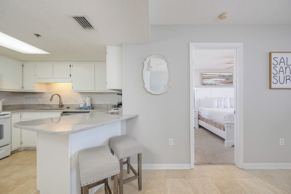 Light spills from the kitchen onto the breakfast bar where you sip morning coffee before exploring the coast