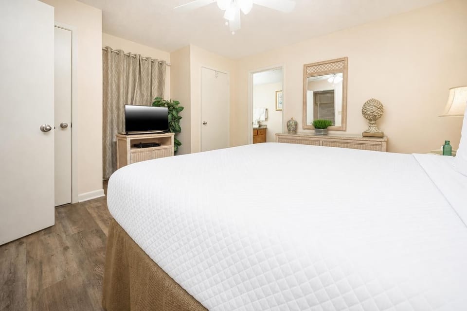 Cozy guest bedroom featuring a plush king bed, TV, and tasteful decor, with a bathroom just steps away