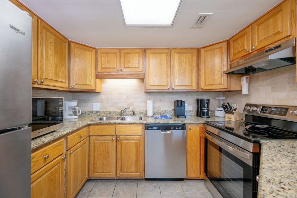 Kitchen featuring warm wood cabinetry, a white dishwasher, and a range of appliances including a Keurig and coffee maker