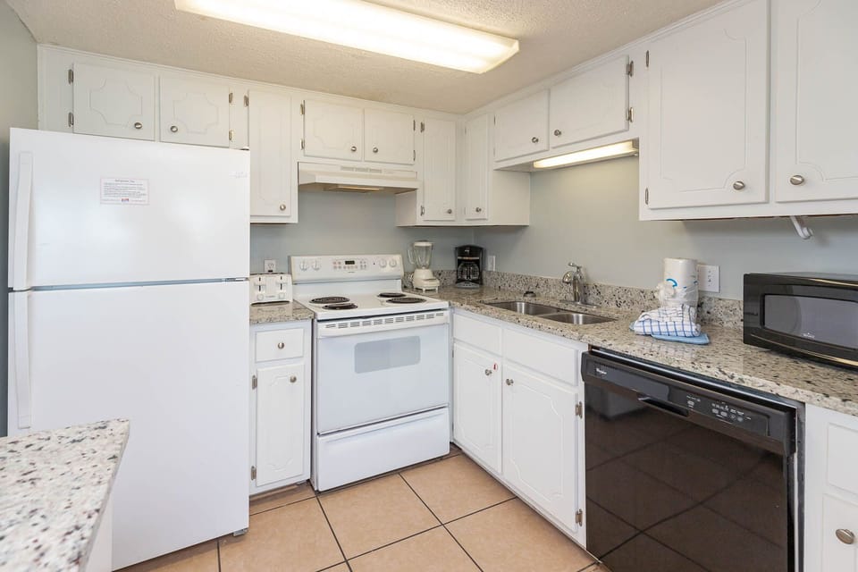 This kitchen features white cabinetry, granite countertops, and essential appliances for a delightful cooking experience