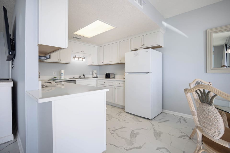 Bright kitchen with white cabinetry, sleek countertops, and a cozy dining area for enjoying meals