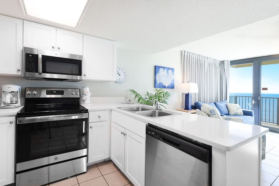 Prepare meals in this kitchen with stainless steel appliances, a spacious countertop, and a view of the inviting living area