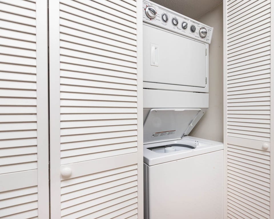 This laundry area features a stacked washer and dryer behind stylish louvered doors for convenient in-unit laundry
