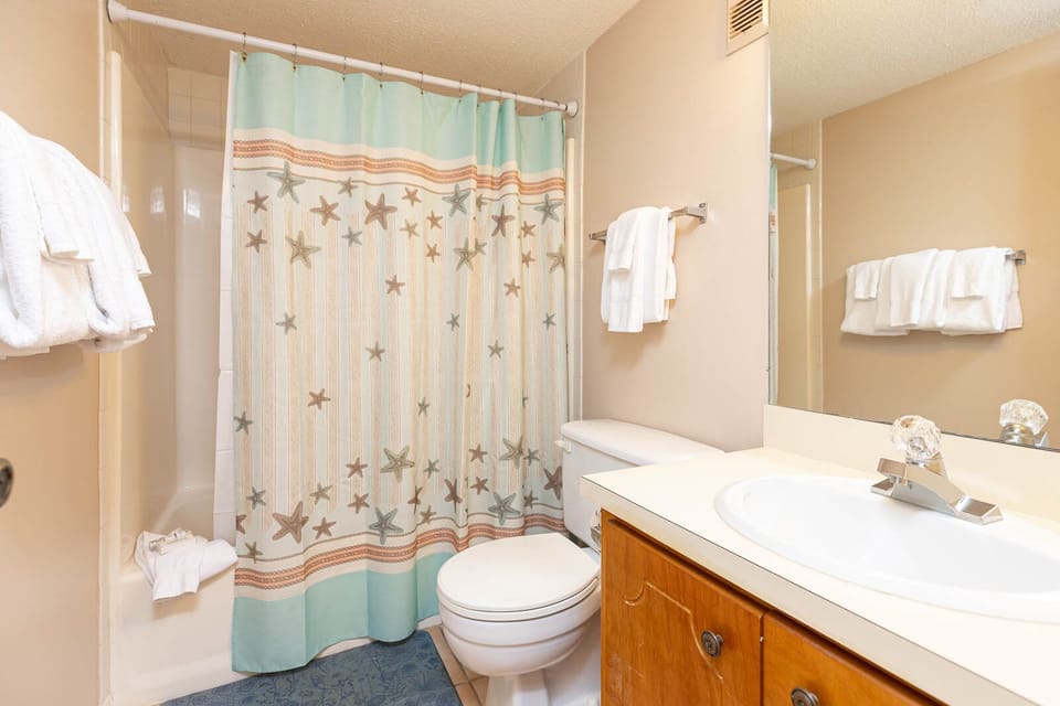 This bathroom features a starfish-patterned shower curtain, fresh towels, and a clean, inviting space for relaxation