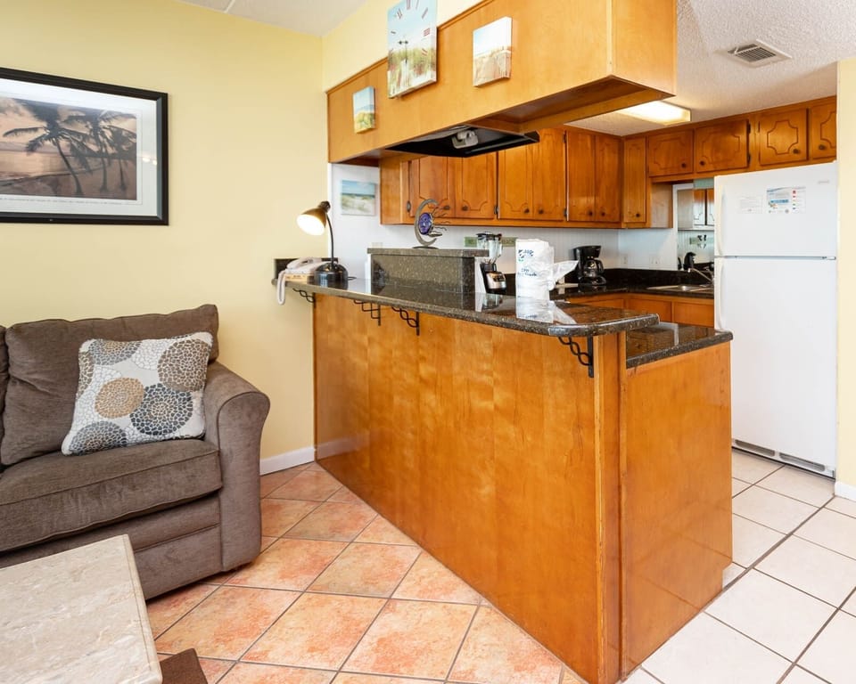 The living area features a comfortable sofa, a stylish coffee table, and a well-equipped kitchen with warm wood cabinetry