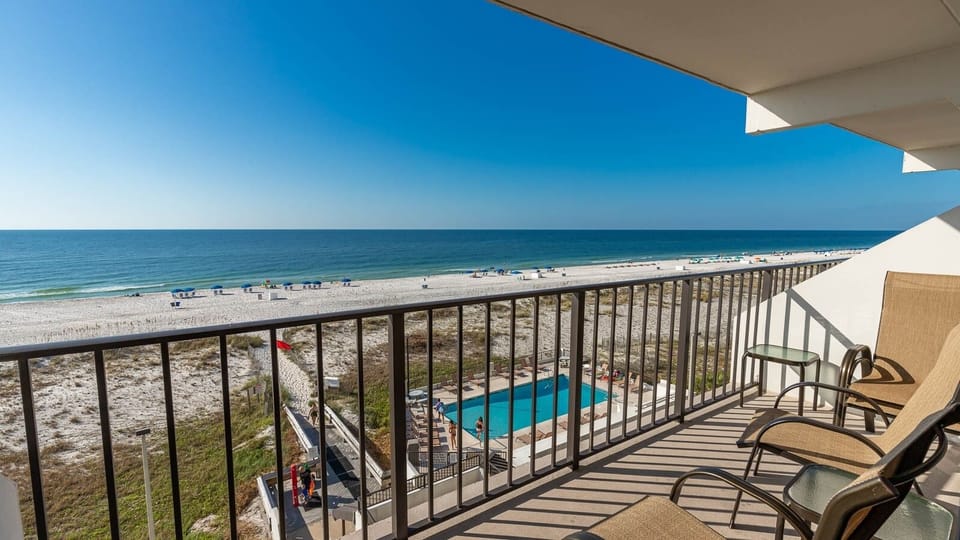 Enjoy stunning beachfront views from the balcony, complete with comfortable seating and a glimpse of the pool below
