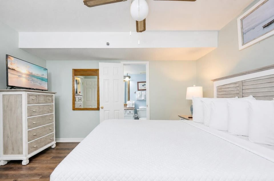 Retreat to the king suite after a day at the beach, featuring soothing decor and a TV for your favorite shows