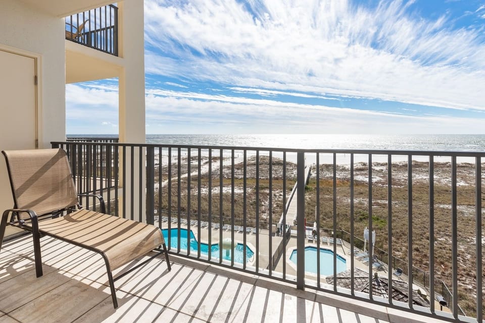 Relax on the balcony lounger while enjoying views of the beach and the inviting pool area below