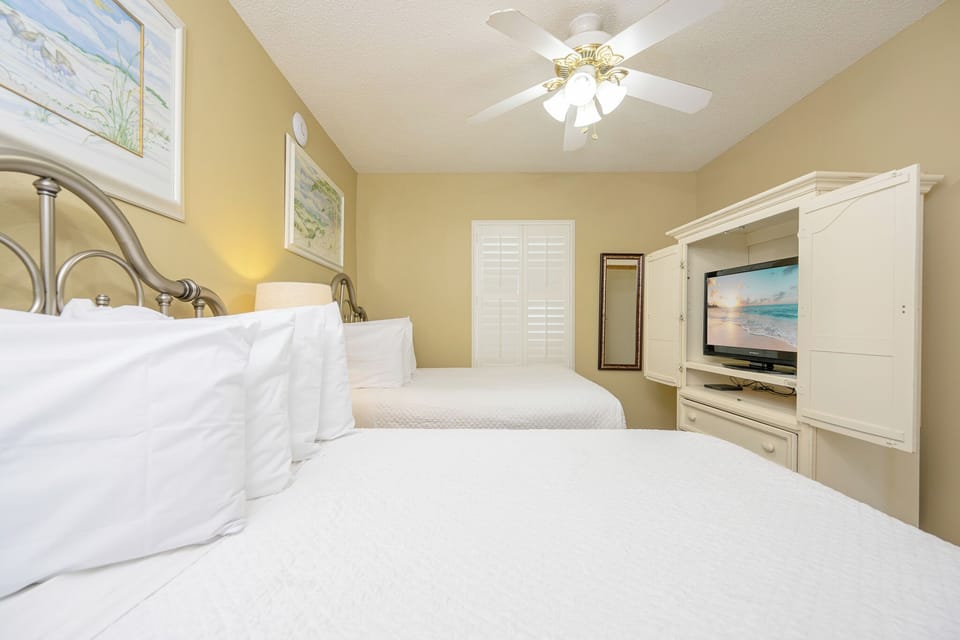 Rest in this comfortable guest bedroom featuring double beds, a TV, and a mirror, perfect for relaxation after a day of fun