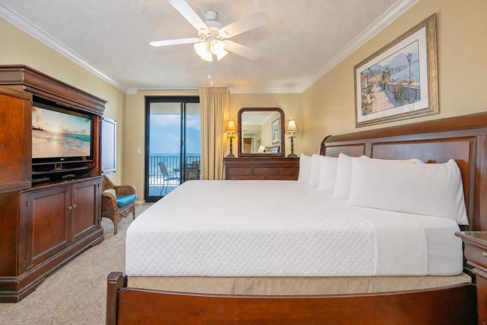 Relax in the inviting master bedroom featuring a king bed, a cozy chair, and easy access to the balcony with beautiful views
