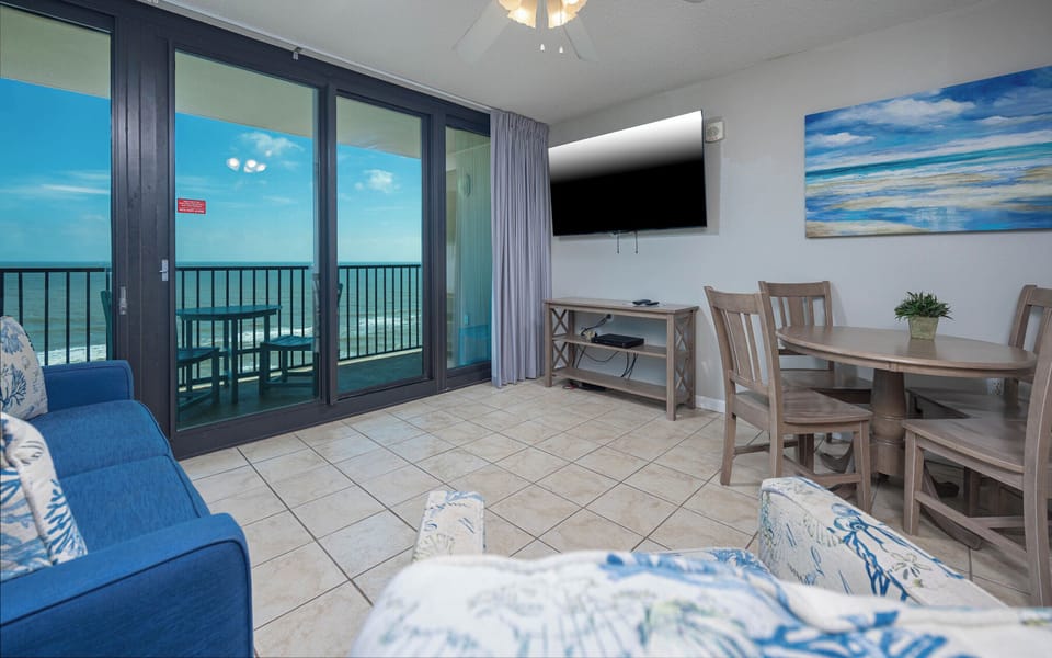 Relax in the comfortable living area, featuring a large TV and easy access to the balcony with beautiful beach views