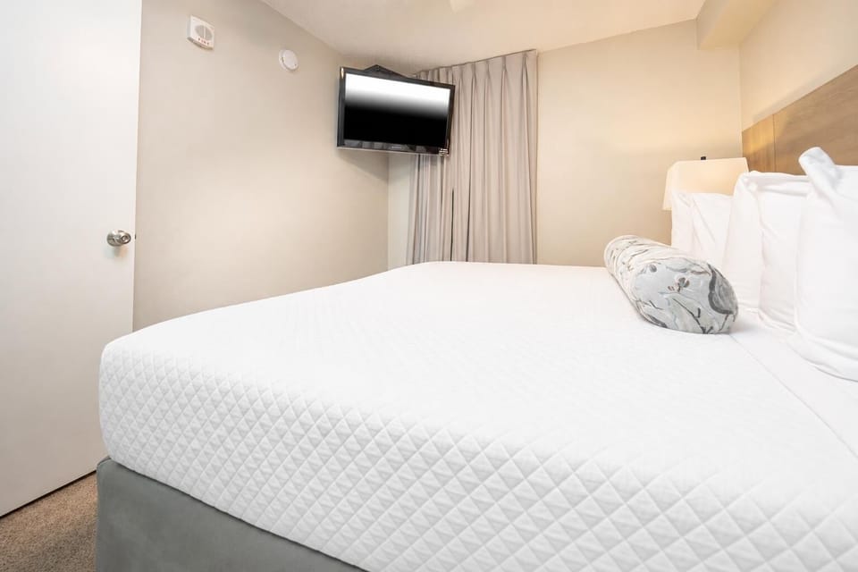 Enjoy restful nights in this cozy bedroom featuring a king bed, soft lighting, and a flat-screen TV for entertainment
