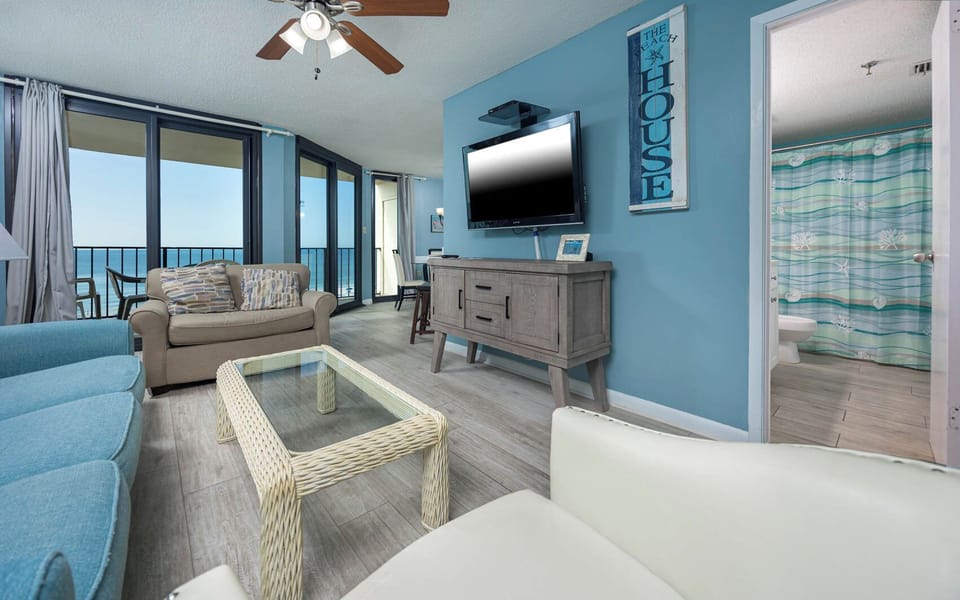 Living area features a cozy sofas with queen sleeper and twin sleeping chair, and a view of the beach through large windows
