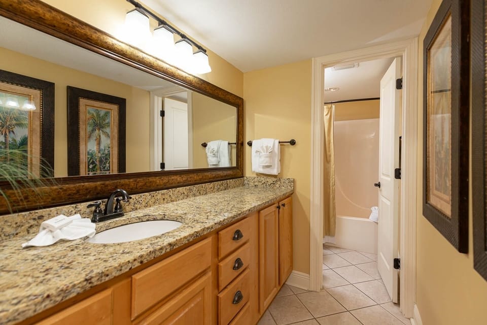 Granite countertop with elegant fixtures and decorative mirrors enhances the warm ambiance of the master bath