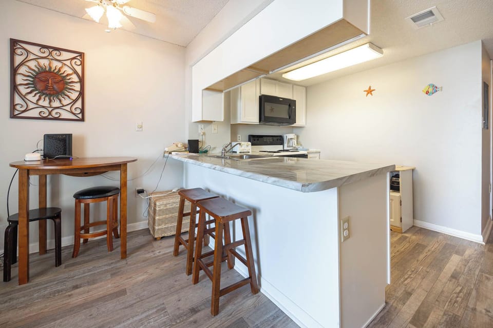 This kitchen features sleek countertops, a black microwave, and a cozy breakfast bar for casual dining