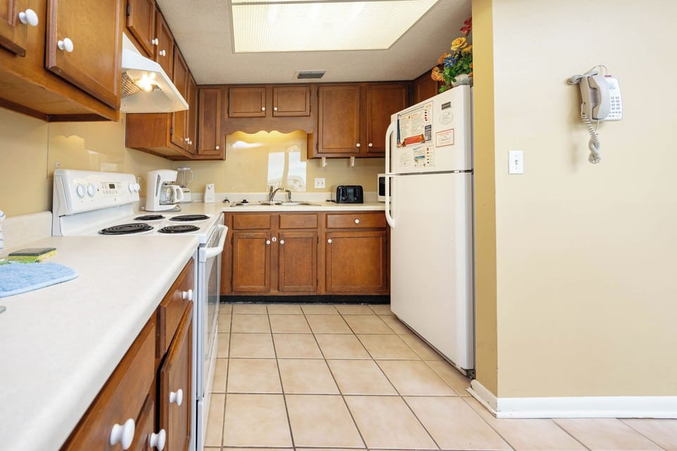 This kitchen features warm wood cabinetry, a full set of appliances, and a convenient coffee maker for your morning brew