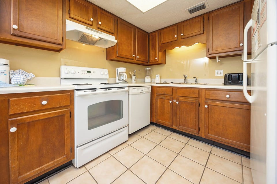 The kitchen features wood cabinetry, white appliances, and a coffee maker for your convenience