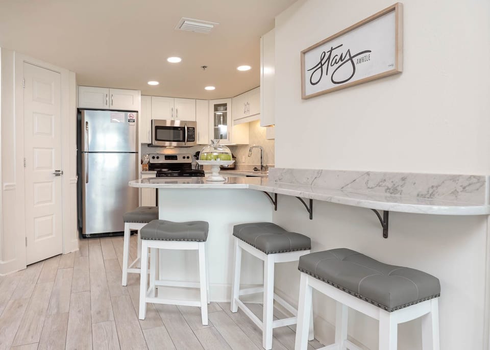 A sleek breakfast bar with gray stools complements the modern kitchen, featuring a marble countertop and stylish decor