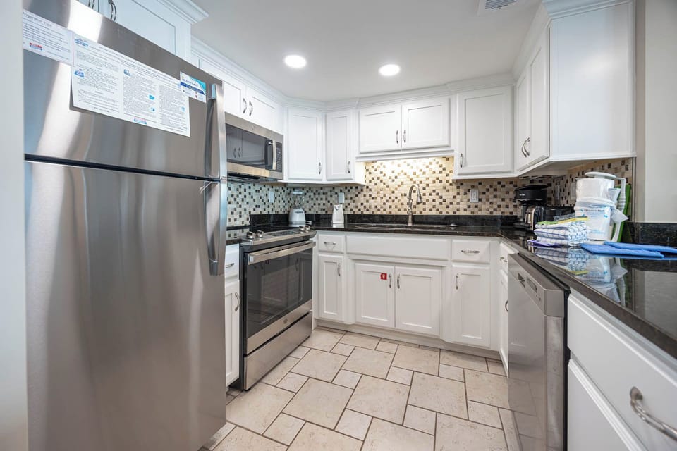 This modern kitchen features stainless appliances, granite countertops, and a stylish tile backsplash for delightful cooking