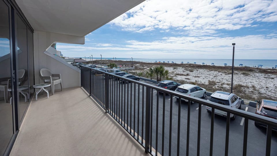 Enjoy a relaxing view from the balcony with seating, overlooking the beach and nearby umbrellas