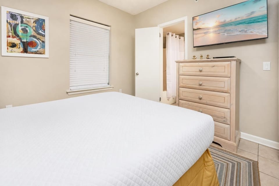 Experience restful nights in this inviting guest bedroom featuring a plush queen bed, a TV, and colorful decor