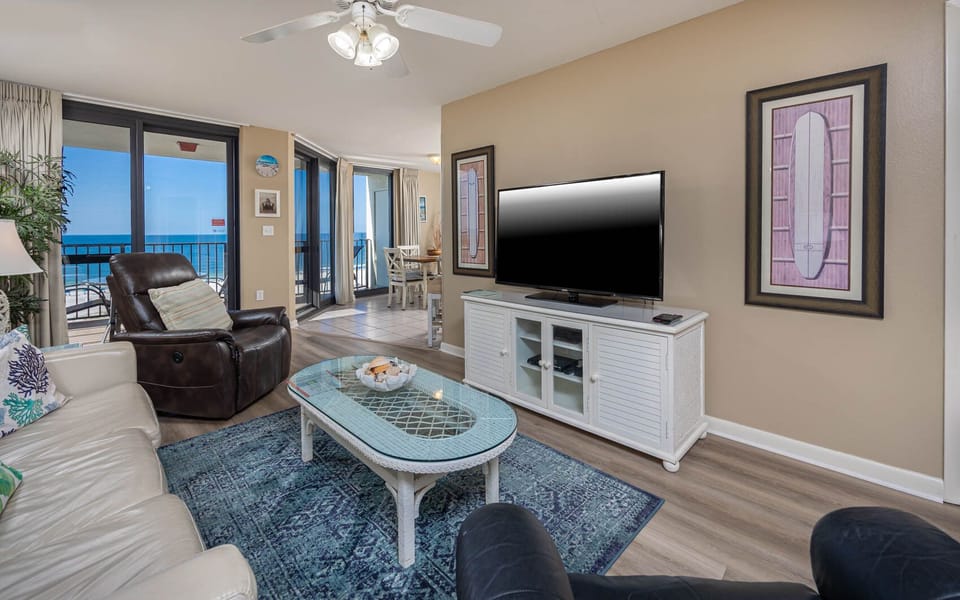 Bright living area features a comfortable leather sofa, large TV, and stunning gulf views through expansive glass doors