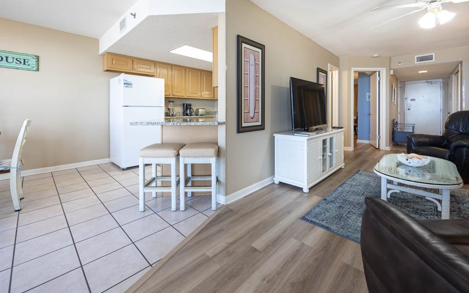 Bright and inviting living area features a comfortable leather chair, a TV, and a breakfast bar with seating