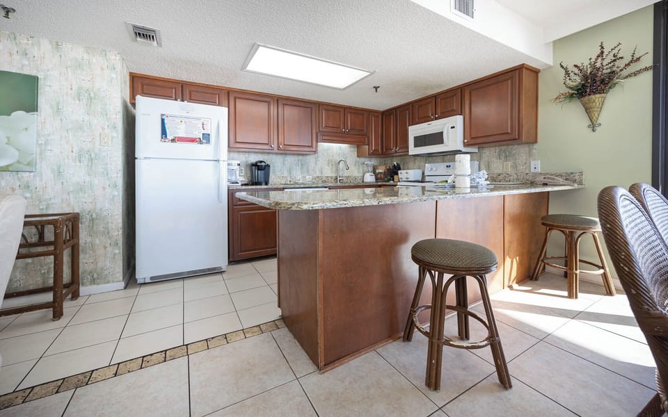 The kitchen features rich wooden cabinetry, granite countertops, Keurig, coffee maker, and breakfast bar with stools