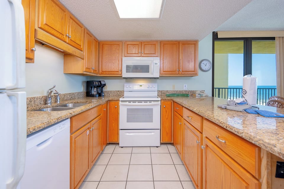 The modern kitchen features warm wooden cabinetry, granite countertops, and a convenient breakfast bar for casual dining