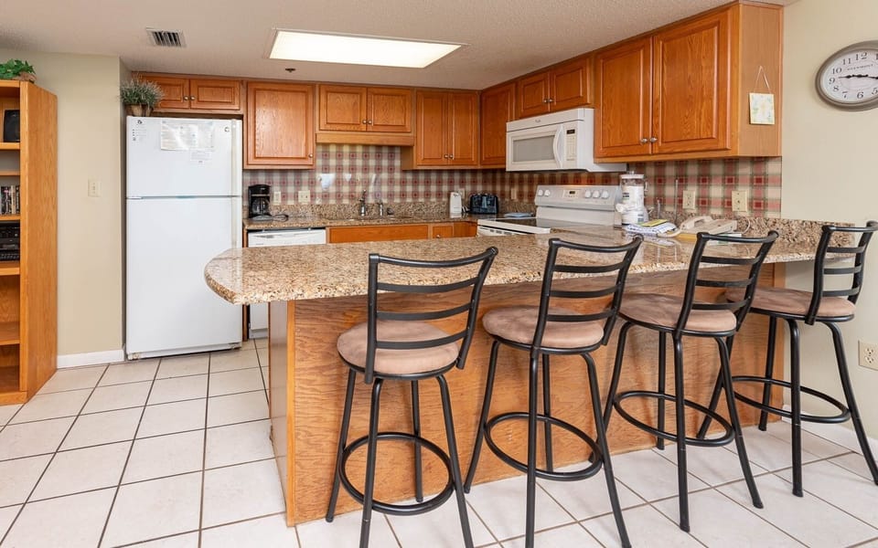 Kitchen featuring wooden cabinets, granite countertops, and a breakfast bar with seating for four, perfect for casual dining