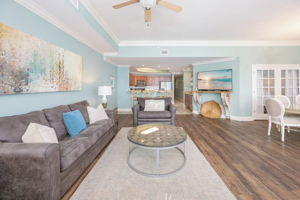 Inviting living area featuring a cozy sofa with queen sleeper, modern decor, and large TV, perfect for entertainment