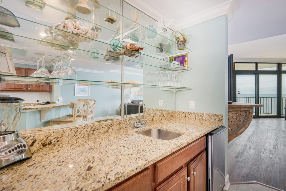 Kitchen wet bar area with granite countertops, stainless appliances, and a view of the serene coastline beyond
