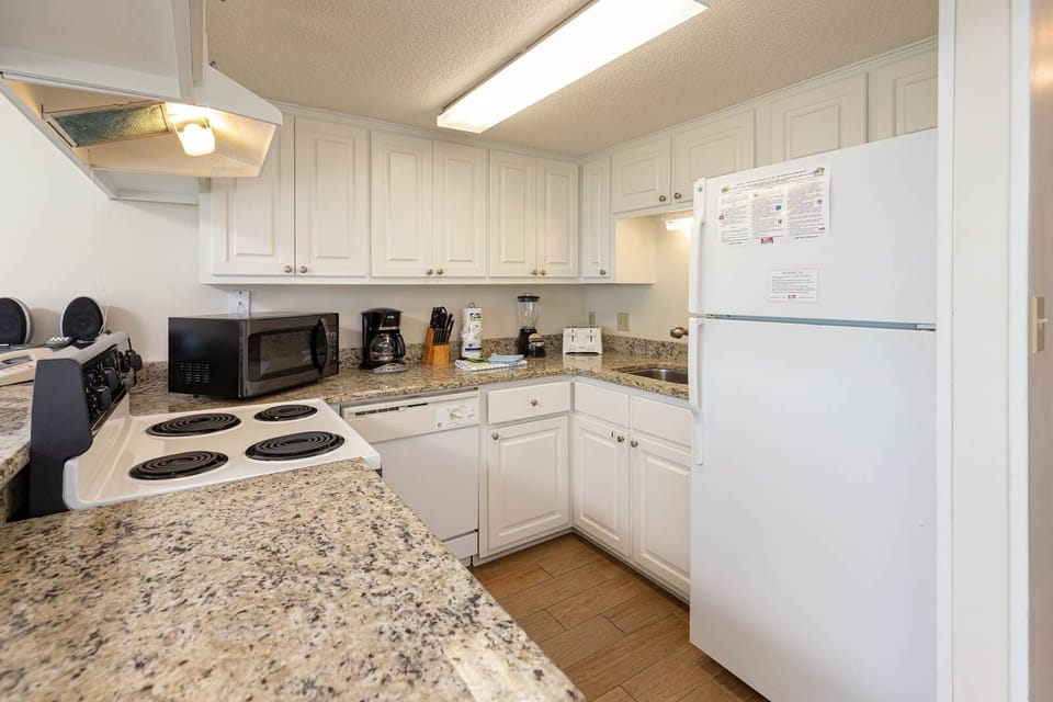 This kitchen features white appliances and ample counter space for preparing meals during your stay
