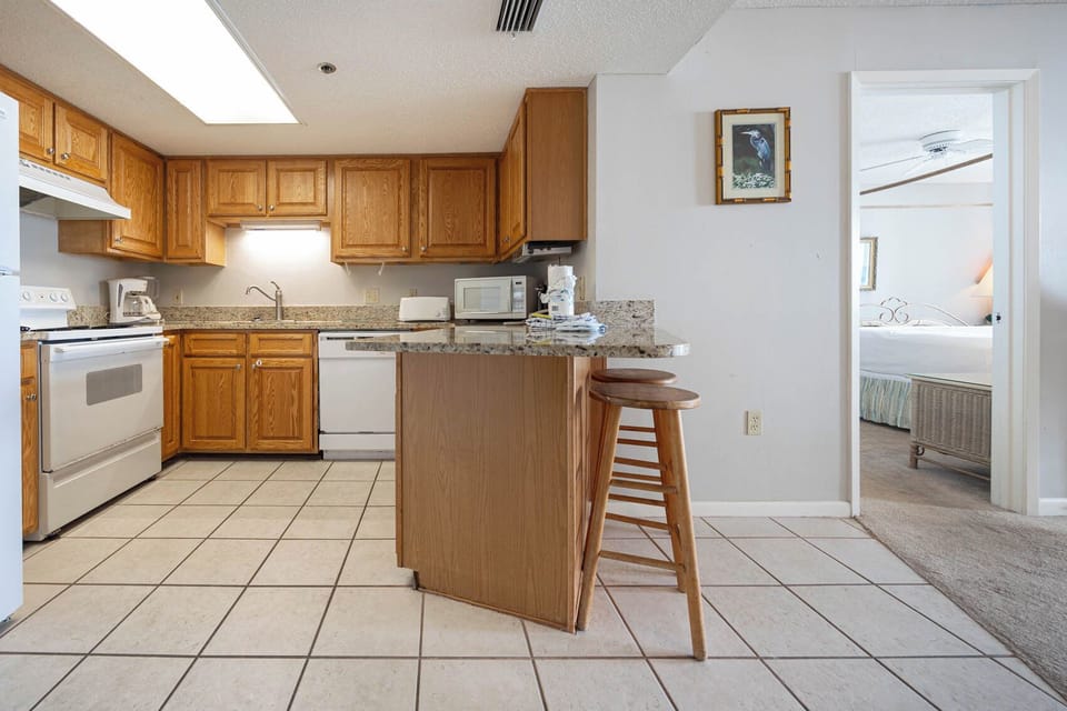 Prepare meals at the kitchen with wooden cabinetry, granite countertops, and a breakfast bar