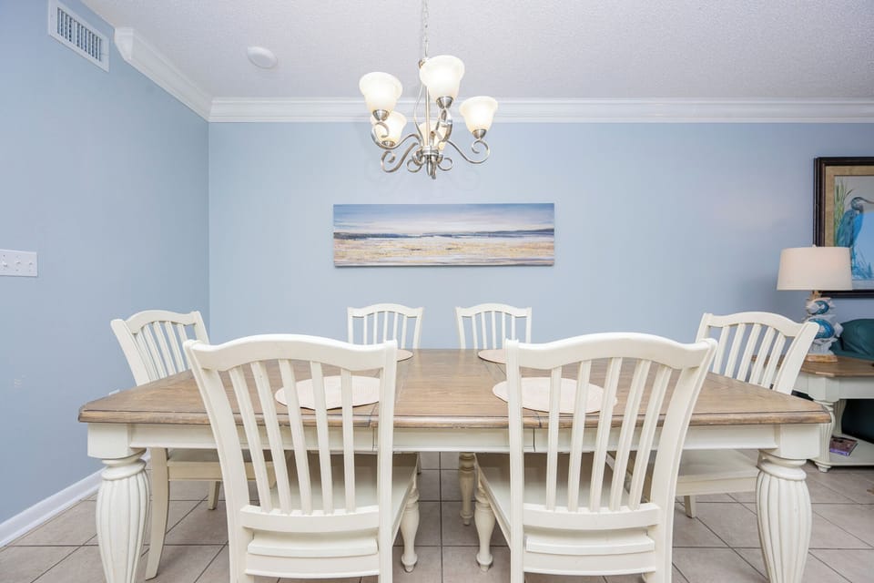 Gather around the rustic dining table, surrounded by light blue walls and coastal artwork, for memorable meals