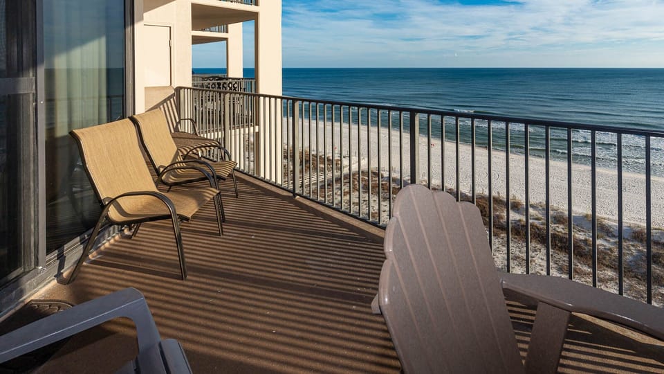 Relax on the balcony in comfortable seating, enjoying expansive views of the water and beach below