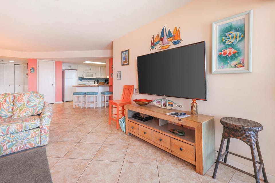 Brightly decorated living area features a colorful sofa, large TV, and a breakfast bar, creating a welcoming vibe