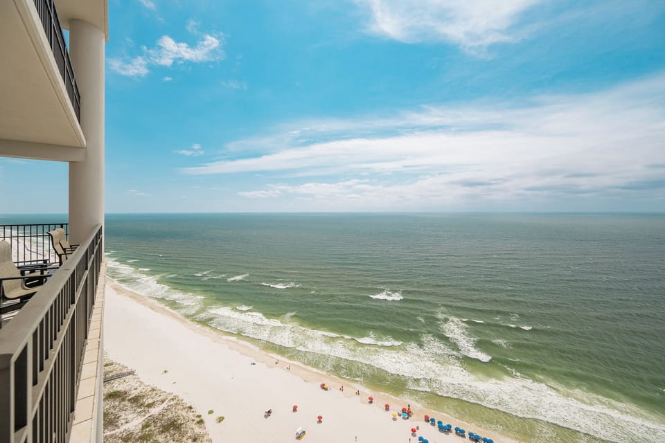 Stunning views of the pristine beach and vibrant umbrellas from a spacious balcony overlooking the sparkling waters