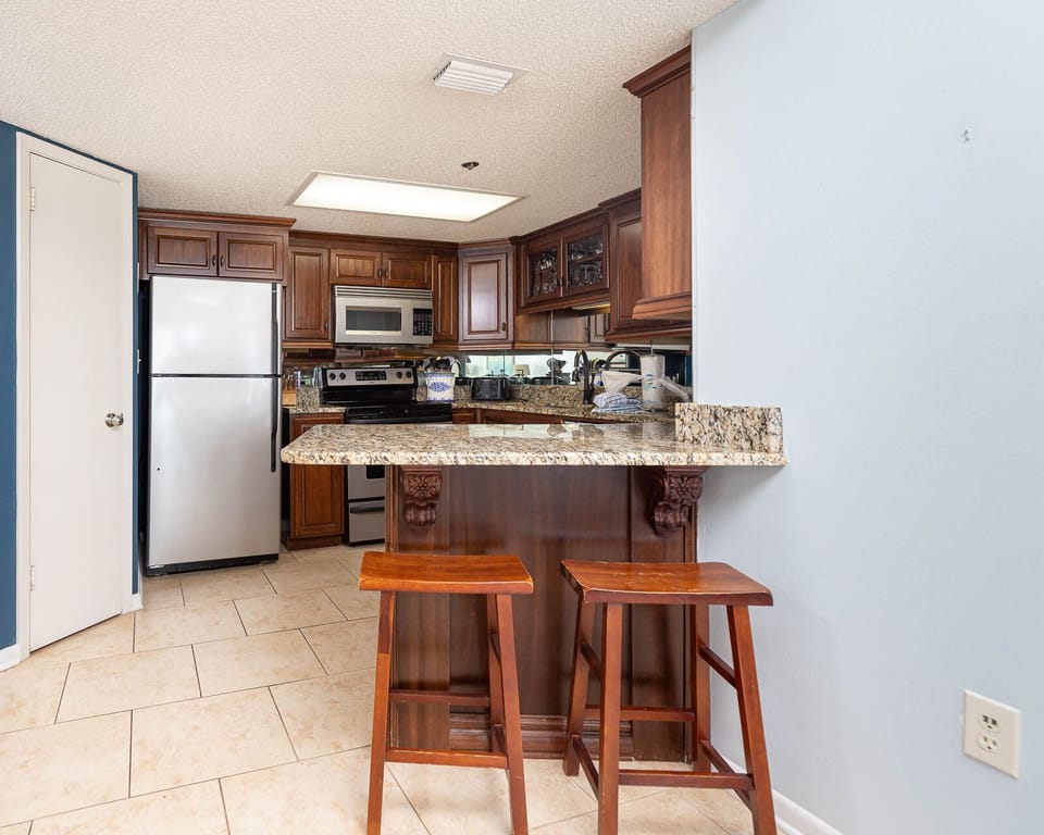 Gather around the granite countertop bar with seating, perfect for casual meals in a welcoming kitchen