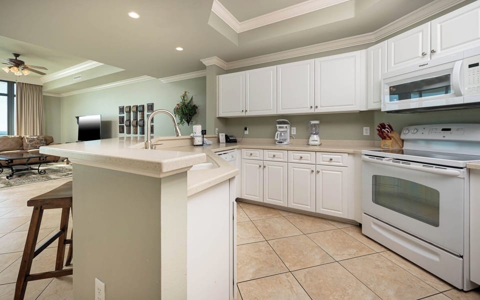 Prepare meals in this kitchen with sleek cabinetry, white appliances, and spacious countertops