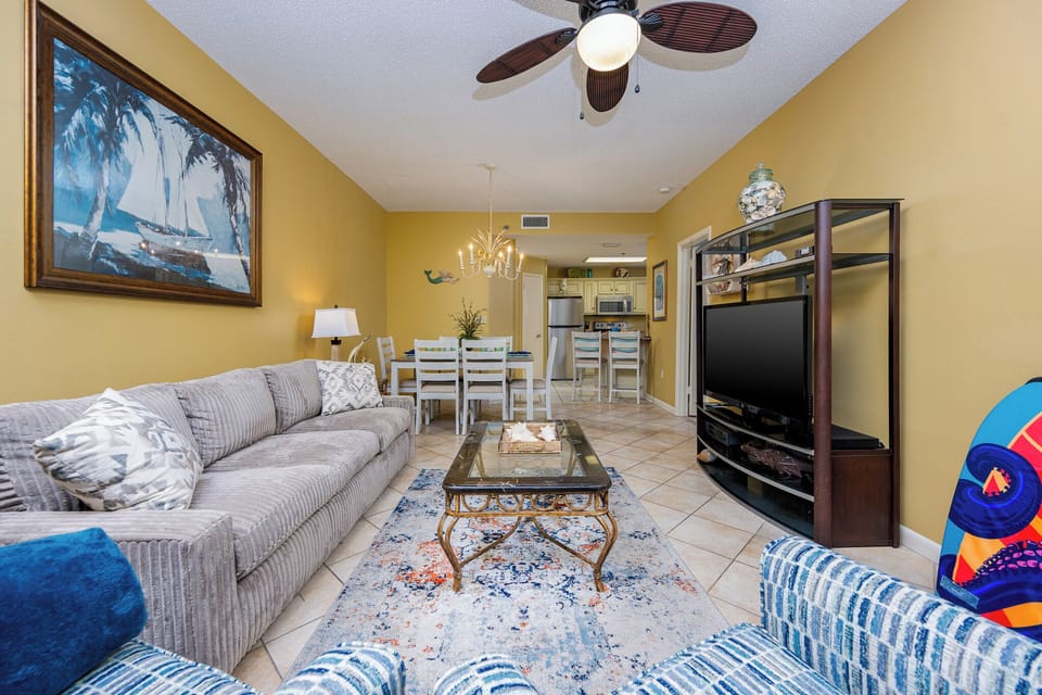 Relax in the spacious living area with plush seating, vibrant decor, and a view leading to the dining space