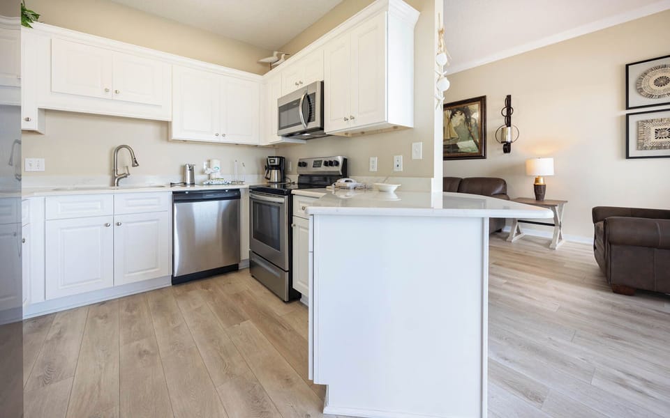 White cabinetry complements the modern kitchen, featuring a breakfast bar and stainless appliances