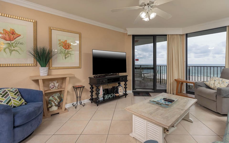 Living area features a sofa with queen sleeper, decorative art, TV, and sliding doors leading to the gulf front balcony