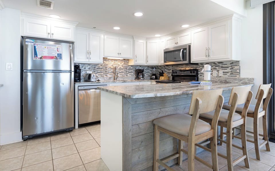 Prepare meals in this sleek kitchen featuring stainless appliances and a spacious bar with seating