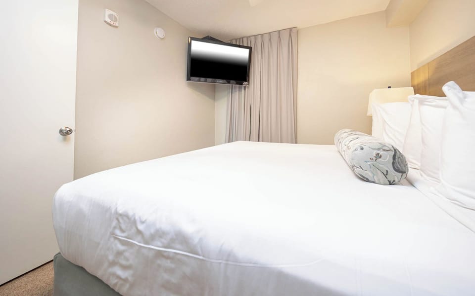 Enjoy restful nights in this cozy bedroom featuring a king bed, soft lighting, and a flat-screen TV for entertainment