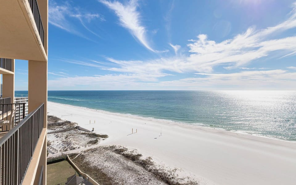 A stunning beachfront view showcases the shimmering water and white sand, inviting relaxation and seaside enjoyment