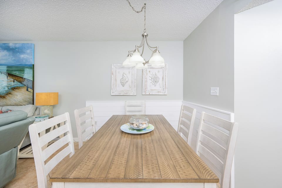 Gather around the wooden dining table, surrounded by coastal decor and soft lighting for memorable meals together