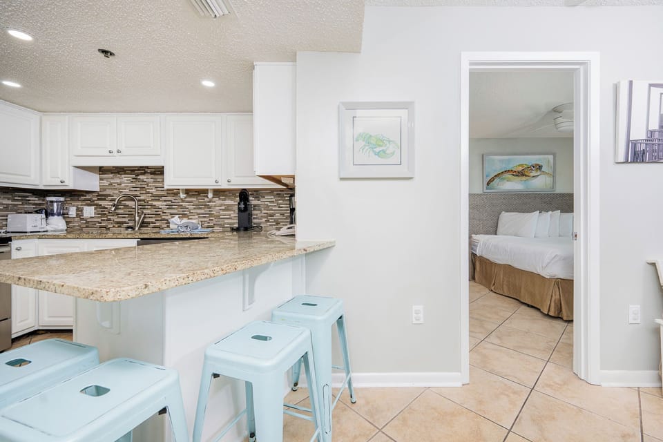 Enjoy casual meals at the breakfast bar with colorful stools, overlooking the stylish kitchen and inviting decor
