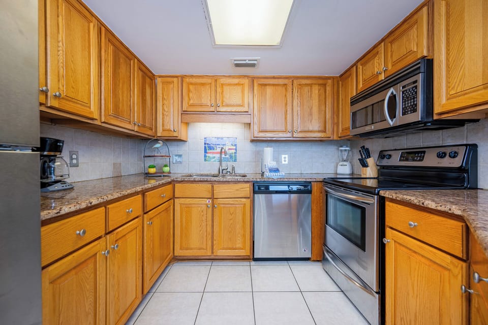 Shiny stainless appliances shine beside warm oak cabinets where you prepare fresh beachside meals